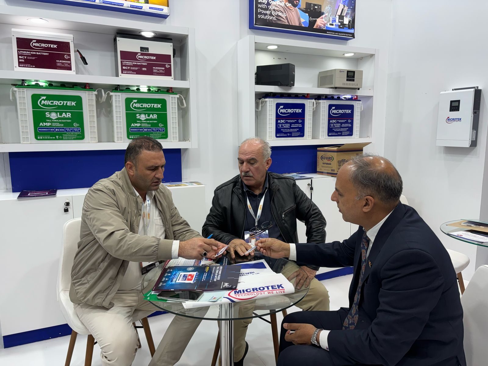 Microtek executive meeting prospective partners at the company's Turkey expo booth — Microtek Lithium-Ion and Solar battery range visible in the background